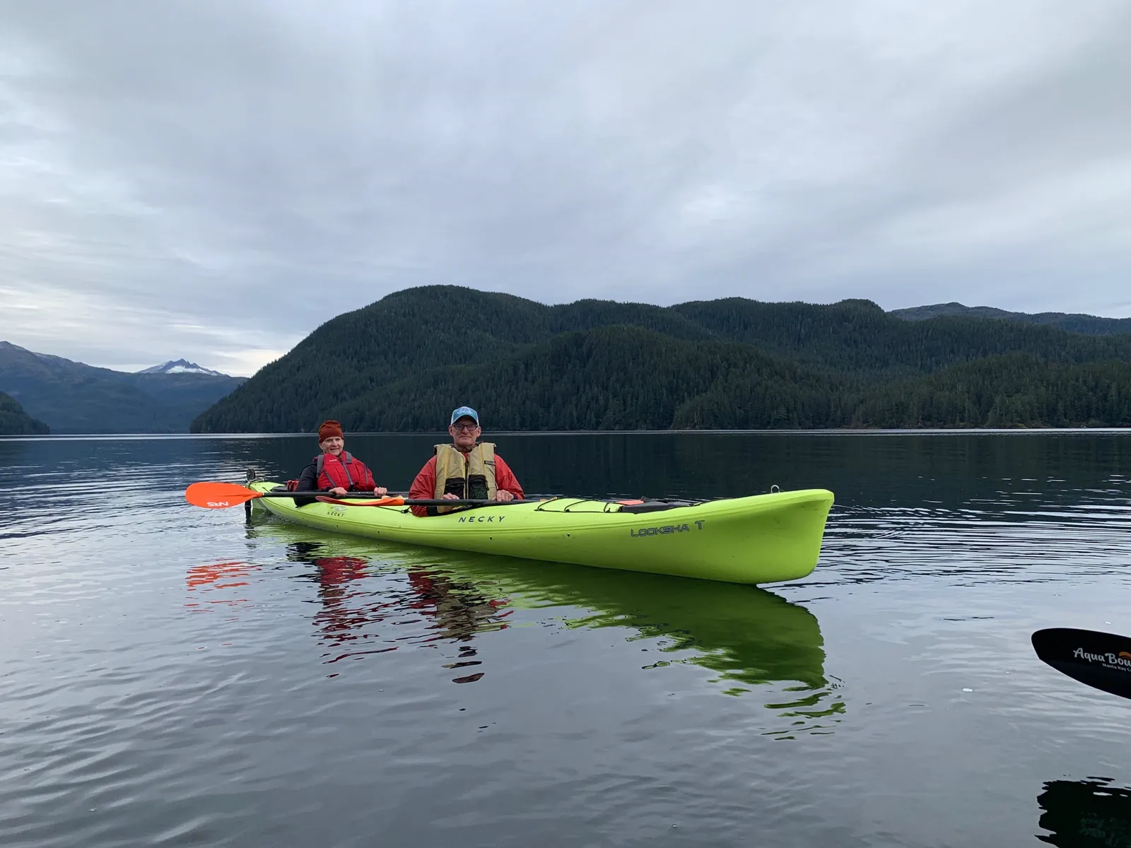Guests in a tandem kayak with Sitka's mountains behind them